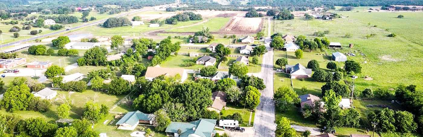 Aerial view of a rural community with homes along a tree-lined street