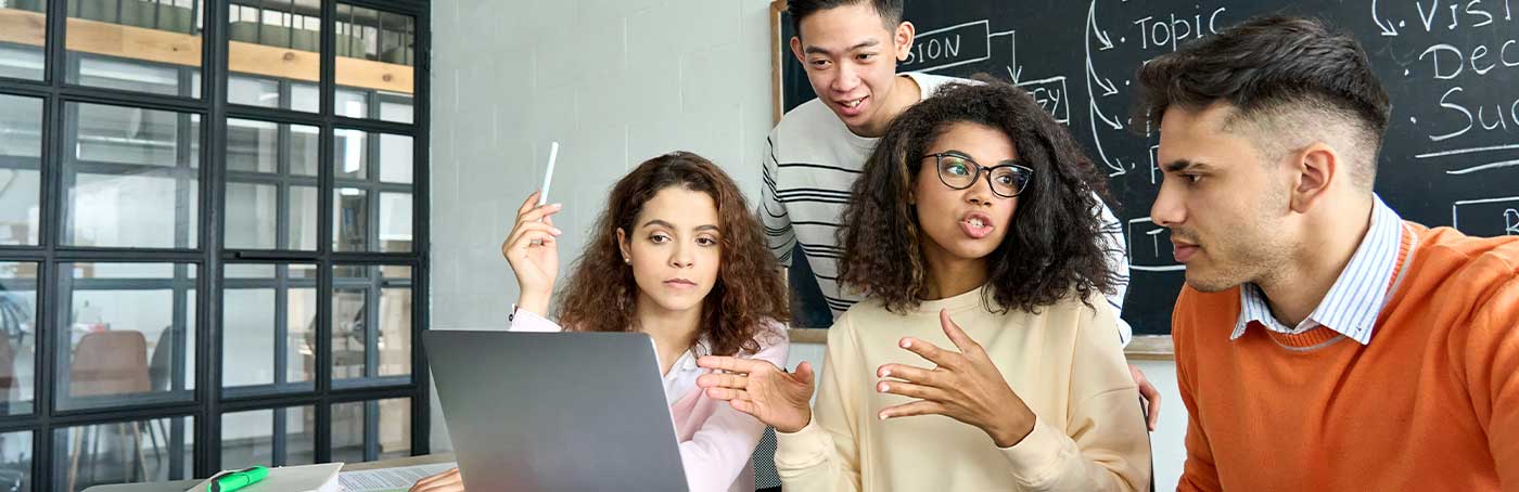 Image of three students looking at a laptop and having a conversation