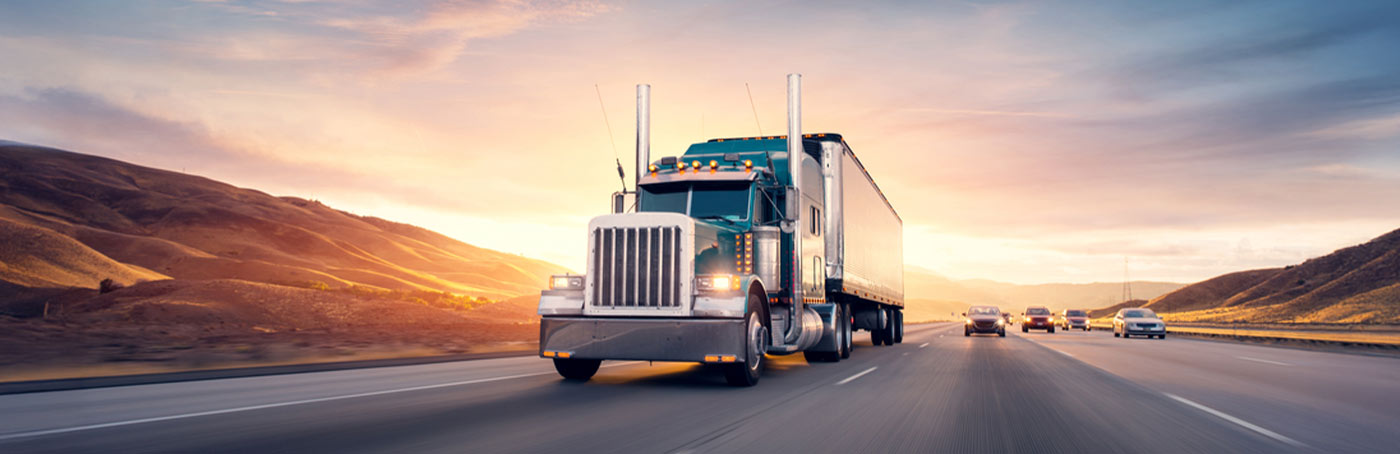 image of a semi-truck on the road, with care driving behind it on a three-lane highway