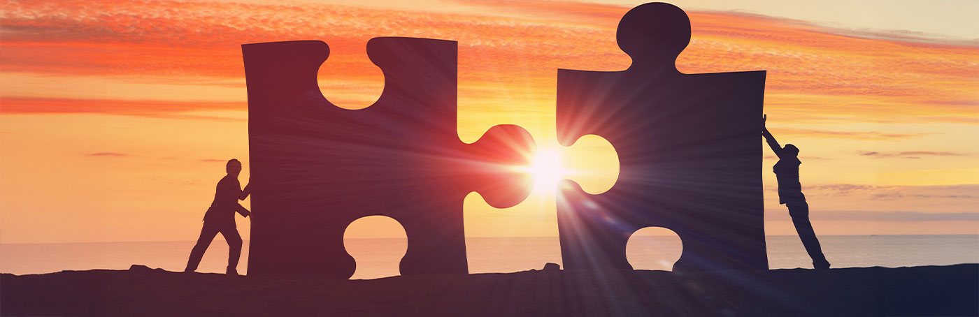 Two people pushing giant puzzle pieces together